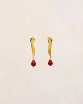 Primer plano de los pendientes bañados en oro de 18 quilates de alargada con piedra semipreciosa en Coral tallada en forma de lágrima