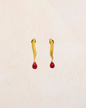 Primer plano de los pendientes bañados en oro de 18 quilates de alargada con piedra semipreciosa en Coral tallada en forma de lágrima