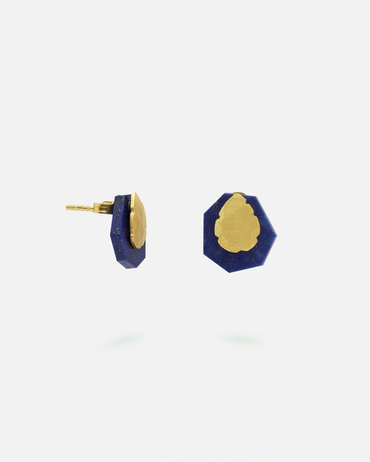 Pendientes pequeños de forma irregular con base en latón bañado en oro y piedra de lapislázuli, ajustados al lóbulo de la oreja.