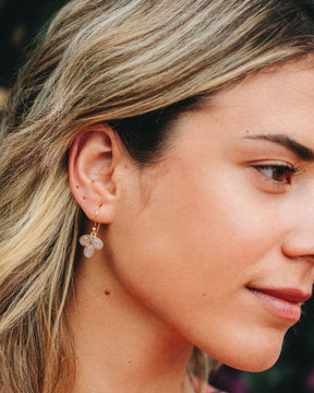 Modelo con pendientes en forma de pétalo con piedra semipreciosa en Cuarzo Melocotón incrustada y cierre de gancho abierto de Isla Vurma