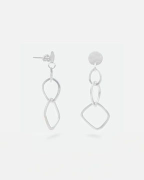 Primer plano de los pendientes geométricos largos bañados en plata 925 de Isla Vurma