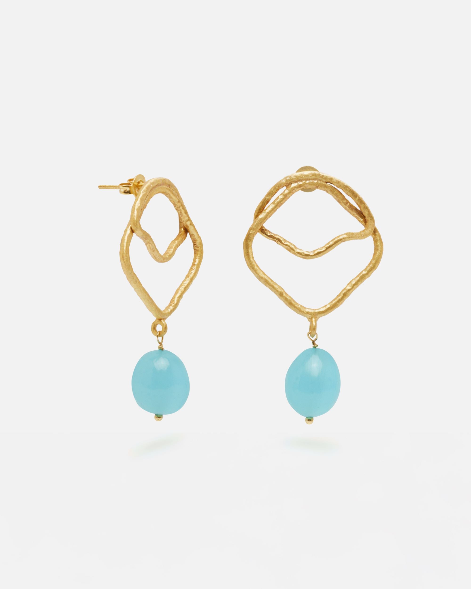 Primer planos de los pendientes asimétricos bañados en oro de 18 quilates con piedra semipreciosa Aqua Calcedonia en forma de aceituna mini, diseño artesanal orgánico de Isla Vurma sobre fondo blanco