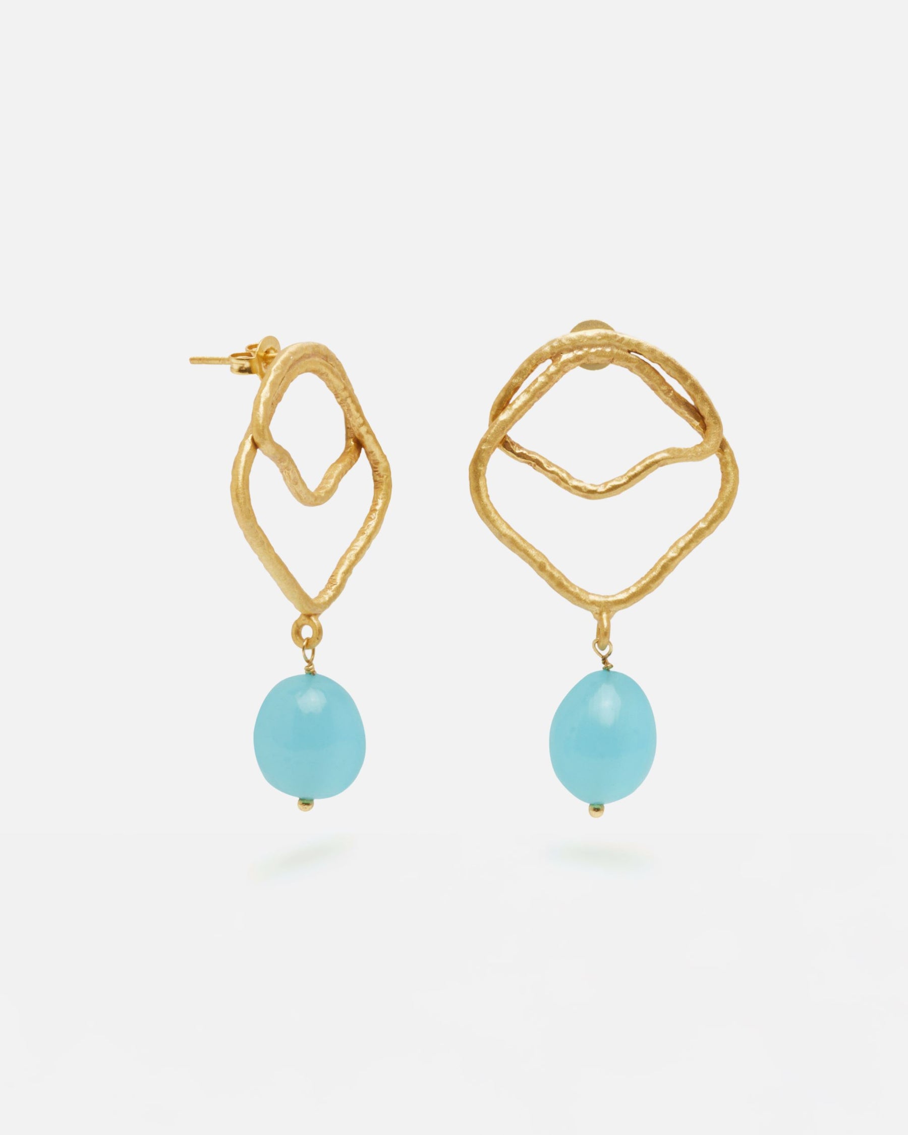 Primer planos de los pendientes asimétricos bañados en oro de 18 quilates con piedra semipreciosa Aqua Calcedonia en forma de aceituna mini, diseño artesanal orgánico de Isla Vurma sobre fondo blanco