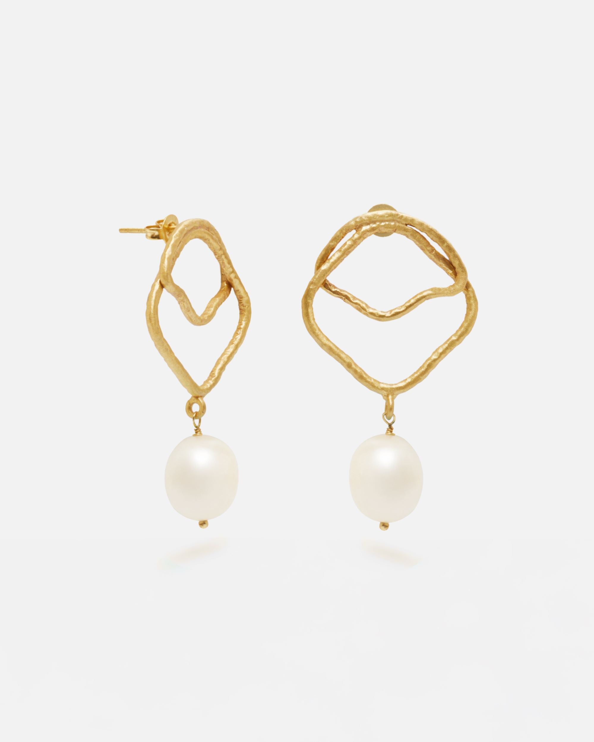 Primer planos de los pendientes asimétricos bañados en oro de 18 quilates con Perla Natural en forma de aceituna mini, diseño artesanal orgánico de Isla Vurma sobre fondo blanco