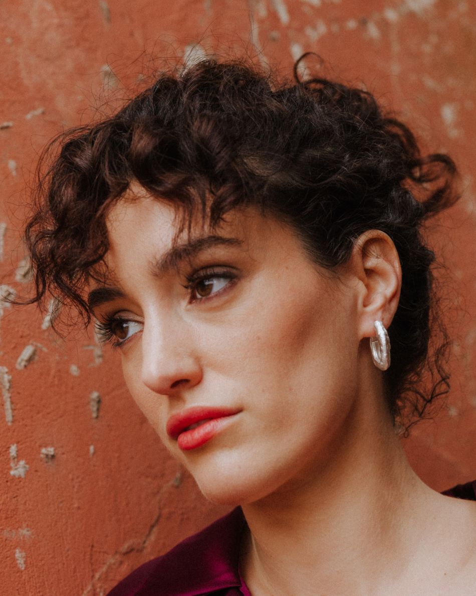 Modelo mirando a la izquierda llevando los pendientes gruesos circulares irregulares bañados en plata 925 de Isla Vurma