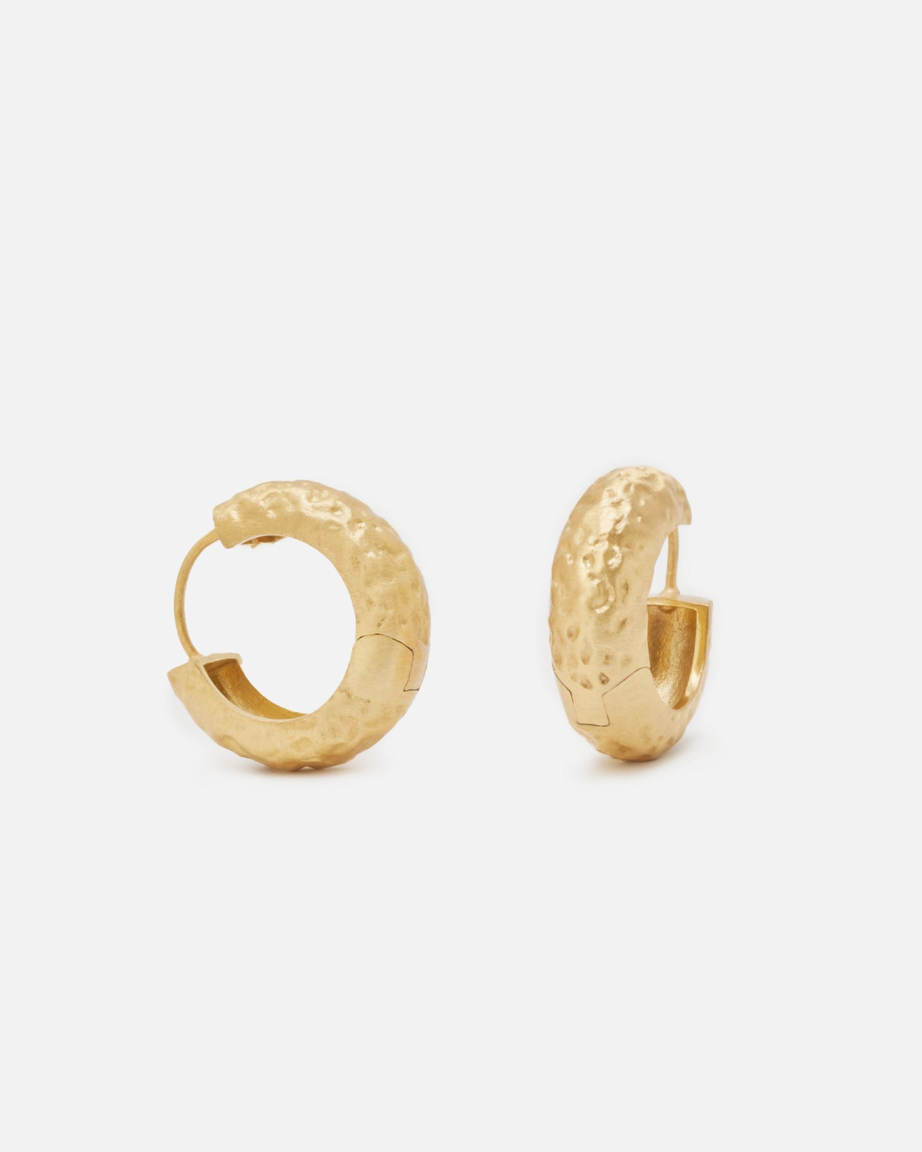 Par de aros dorados de grosor medio con textura martillada y cierre oculto, sobre fondo blanco.