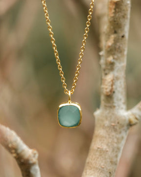 Primer plano del collar con pieza cuadrada disponible en Aqua Calcedonia, en un fondo natural de Isla Vurma