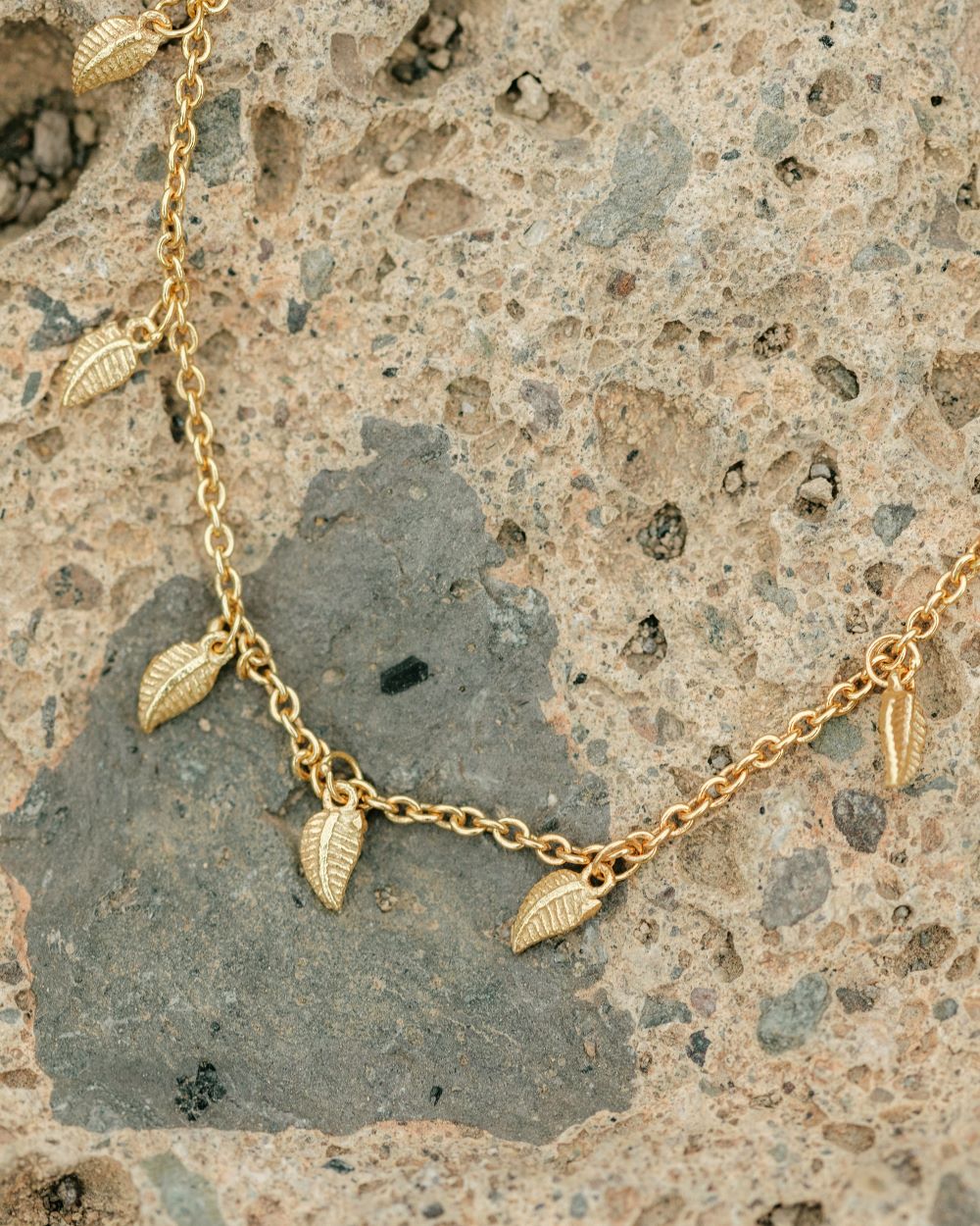 Collar de pequeñas plumas bañadas en Oro sobre una roca