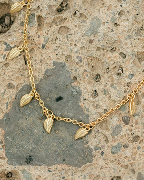 Collar de pequeñas plumas bañadas en Oro sobre una roca