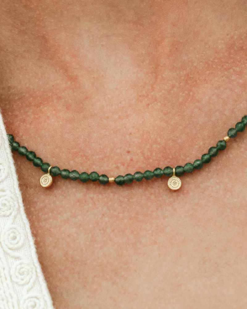 Collar de cuentas Jade con pequeños colgantes dorados sobre el cuello de una modelo de Isla Vurma