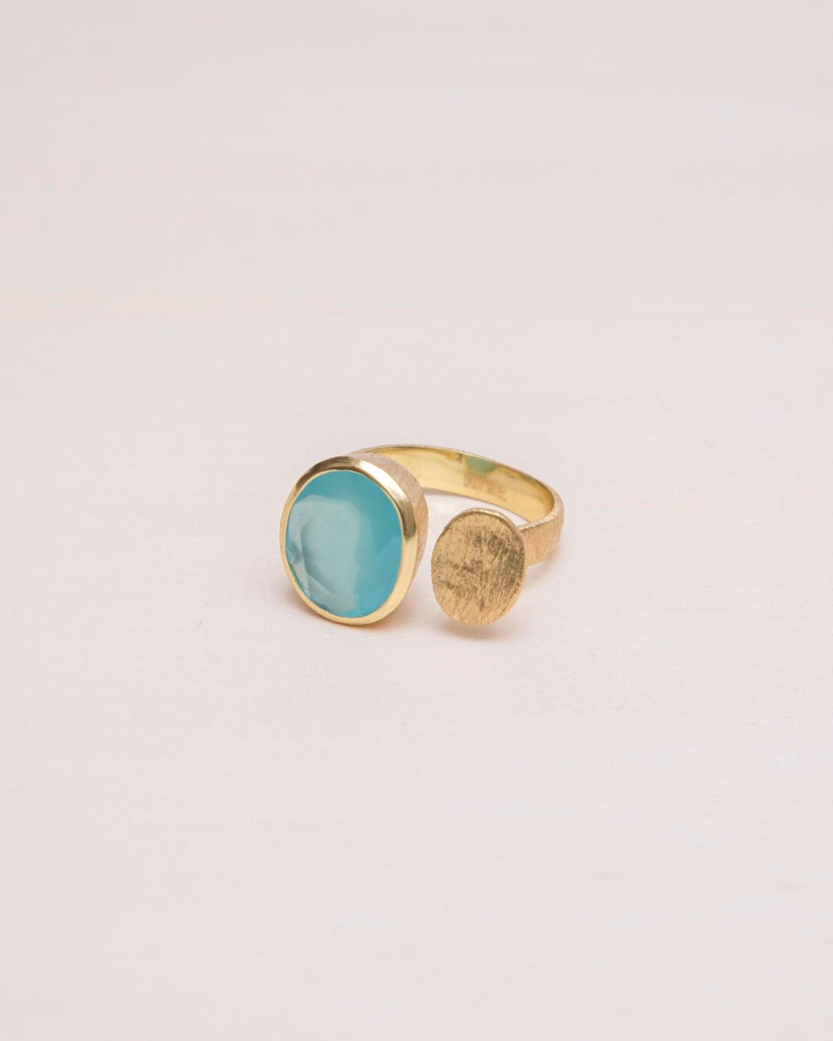 Primer plano del anillo abierto bañado en oro de 18k con piedra semipreciosa en forma circular en Aqua Calcedonia de Isla Vurma