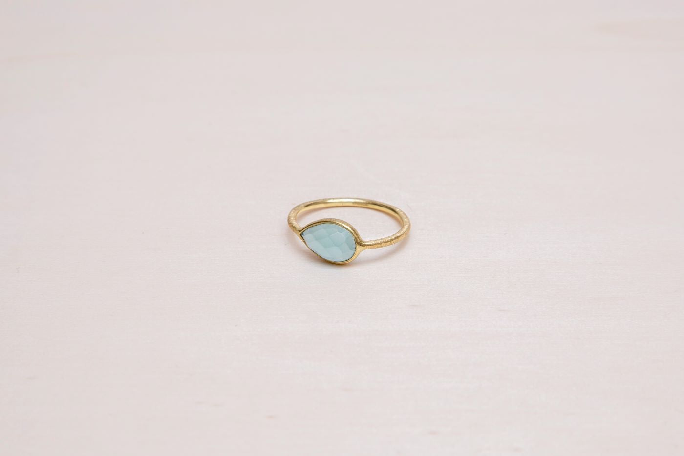 Primer plano del anillo bañado en oro de 18 quilates con piedra semipreciosa en forma de gota en Aqua Calcedonia de Isla Vurma