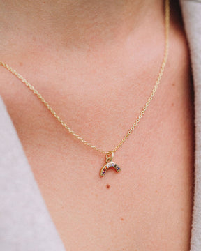 Modelo con collar dorado en forma de arcoiris con piedras semipreciosas incrutadas de Isla Vurma