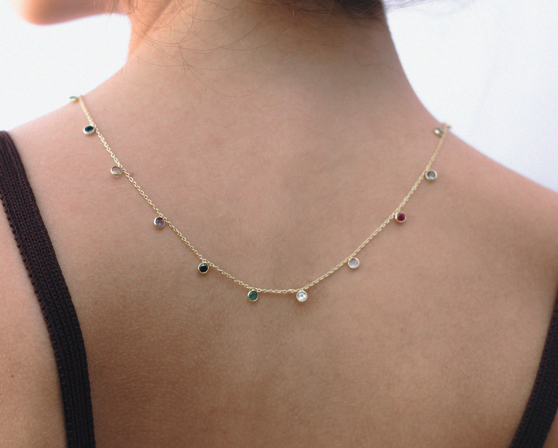 Collar dorado con piedras semipreciosas de Cuarzo rosa, Ónix Verde, Topaz, Sapphire, Ruby, colgando hacia la parte de la espalda de la modelo de Isla Vurma