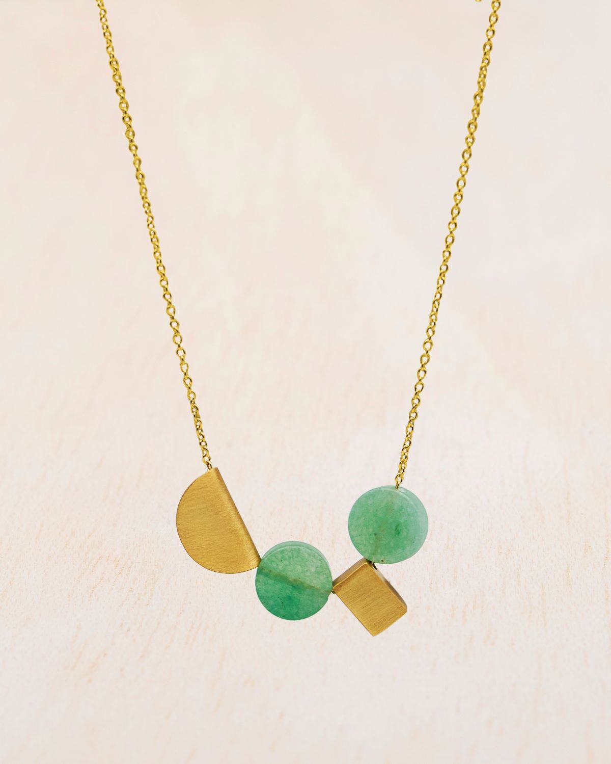 Primer plano del collar bañado en oro con dos piezas geométricas y dos piezas circulares de piedras semipreciosas Aventurina Verde de Isla Vurma