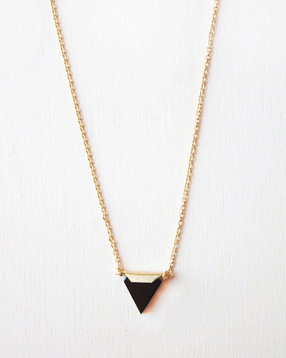 Cadena de latón bañada en Oro de 18 quilates y pieza de ónix negro triangular.