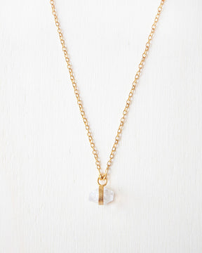 Primer plano del collar bañado en oro de 18 quilates, con piedra semipreciosa Piedra de Luna, sujetada por una pequeña pieza rectangular dorada de Isla Vurma