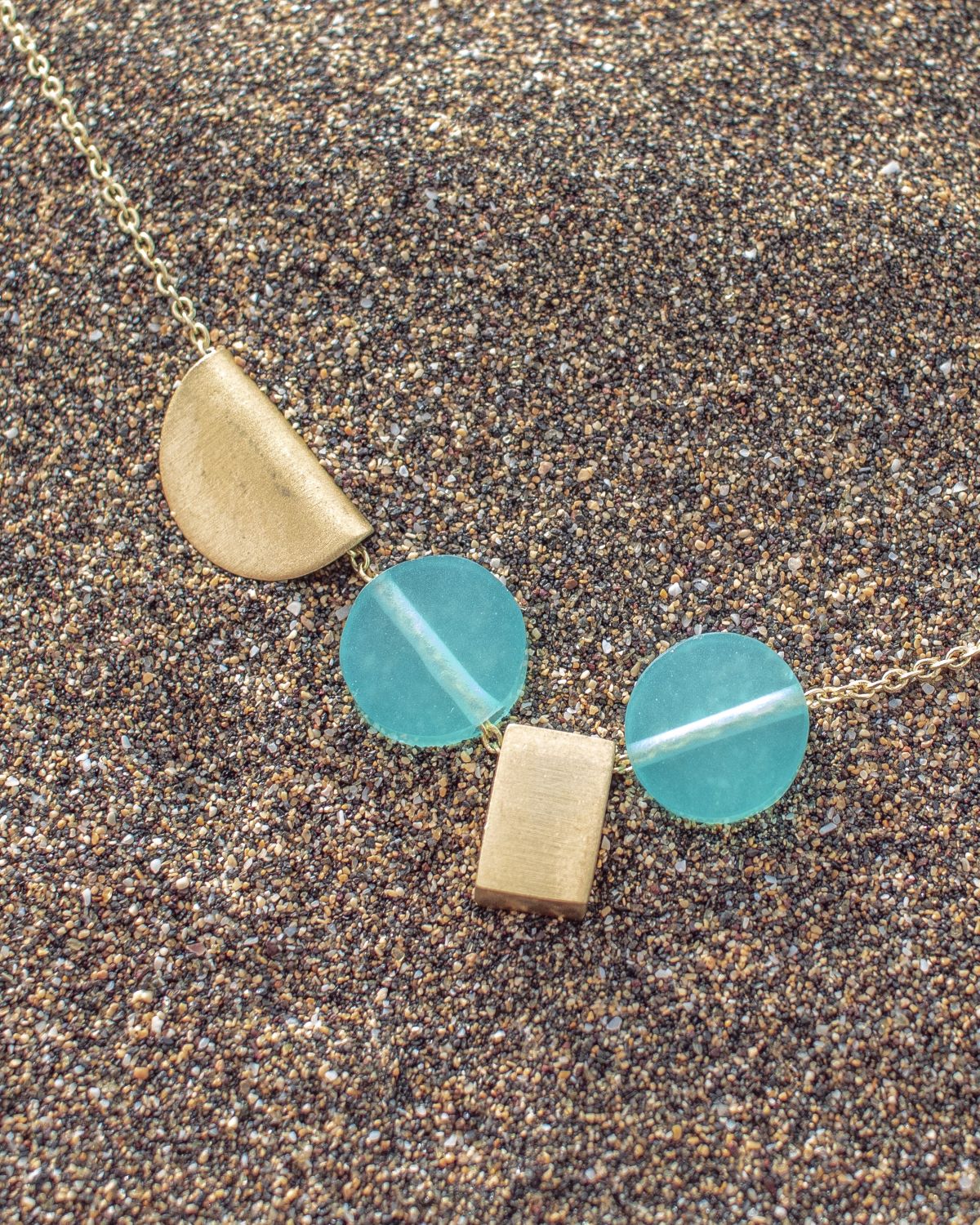Primer plano del collar con piezas geométricas doradas y dos piedras semipreciosas Aqua Calcedonia de Isla Vurma