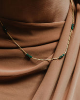 Modelo con camiseta marrón y collar dorado compuesto por pequeñas tiras de piedras semipreciosas Jade de Isla Vurma