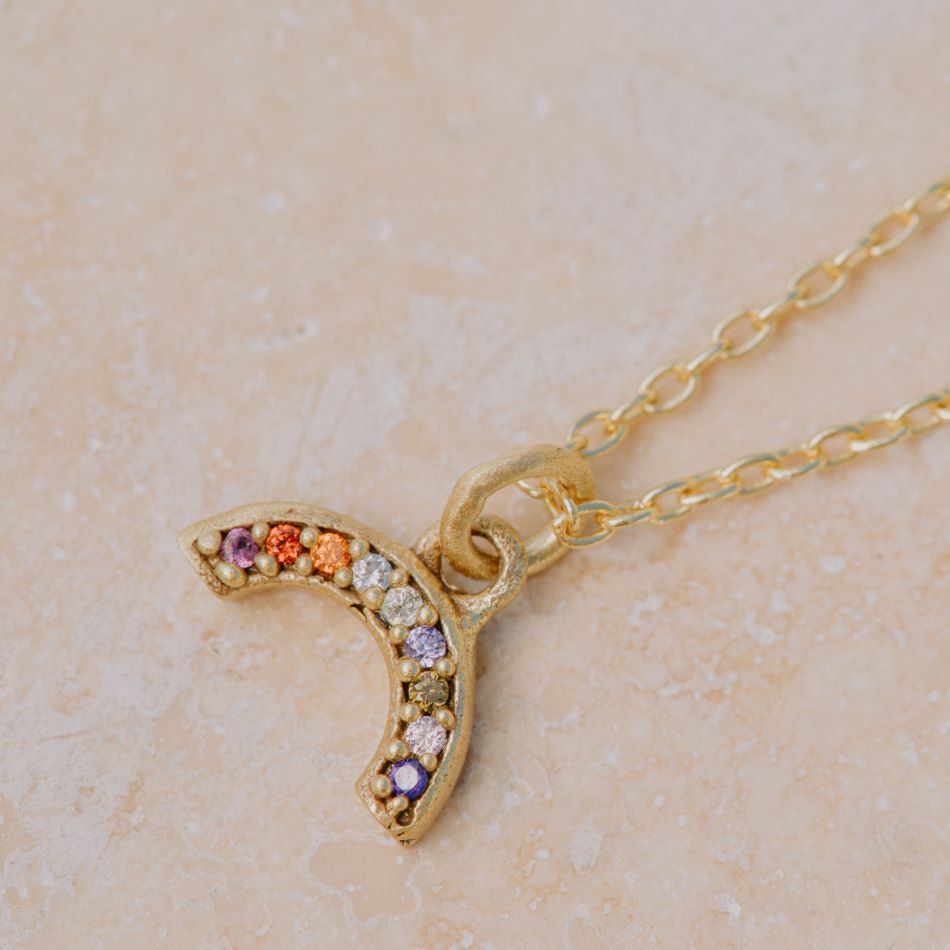 Primer plano de collar bañado en oro y pieza de arcoiris con piedras semipreciosas incrutadas de Isla Vurma