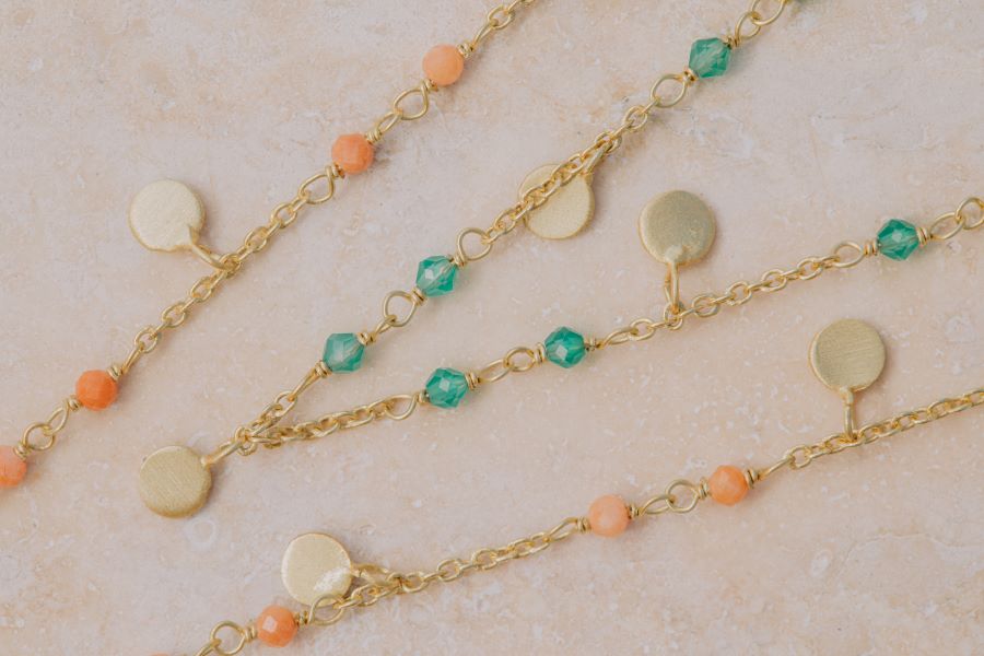 Plano del conjunto de collares bañados en oro, compuesto por piedras Aqua Calcedonia, Piedra de Luna Melocotón y pequeños discos dorados de Isla Vurma