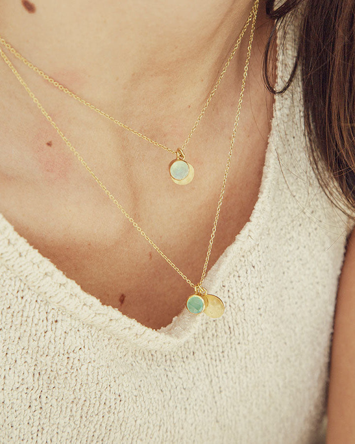 Primer plano del collar acabado en oro 18k con piedra semipreciosa aqua calcedonia y otro en Piedra de Luna de Isla Vurma