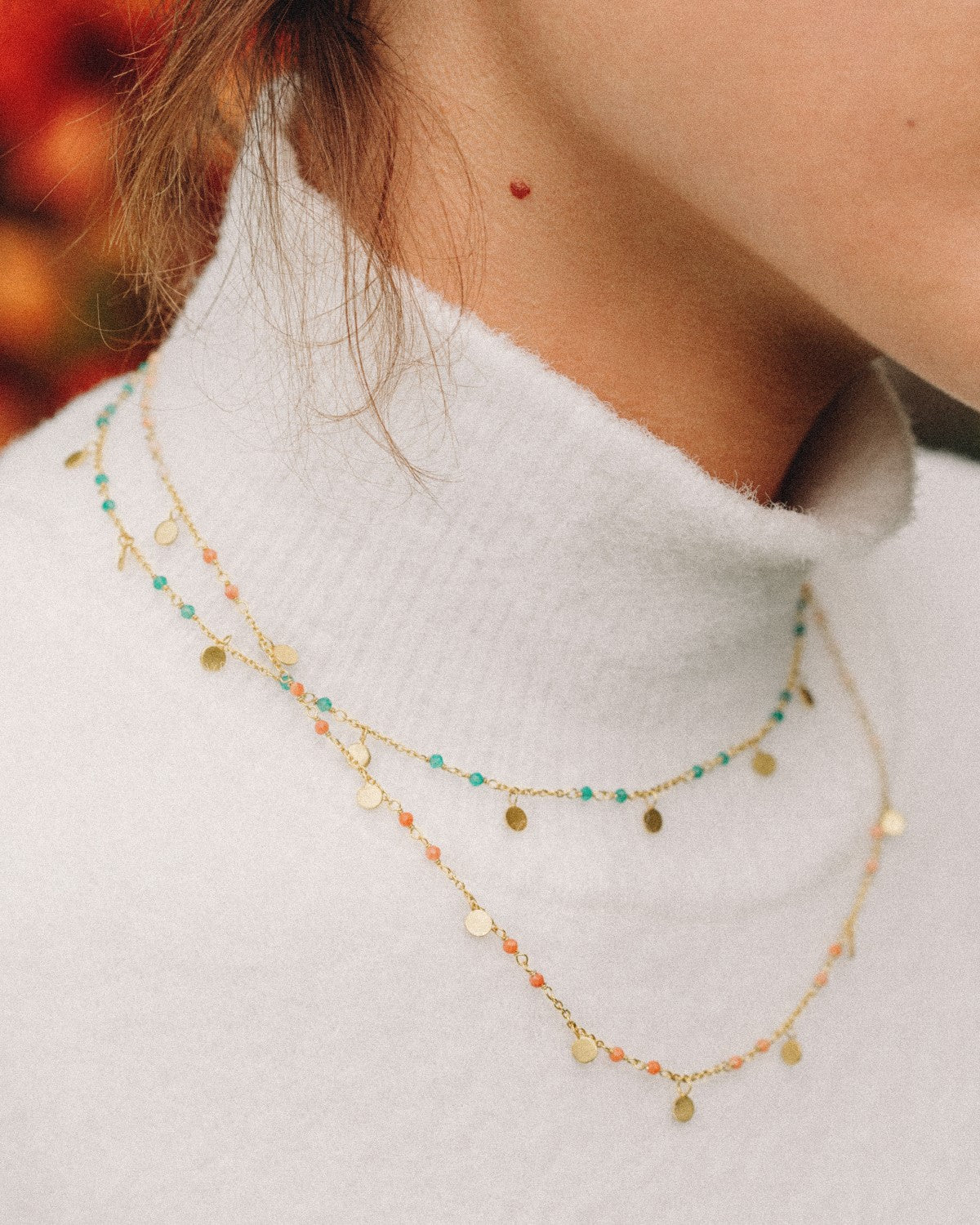 Modelo con conjunto de collares bañados en oro, compuesto por piedras Aqua Calcedonia, Piedra de Luna Melocotón y pequeños discos dorados de Isla Vurma