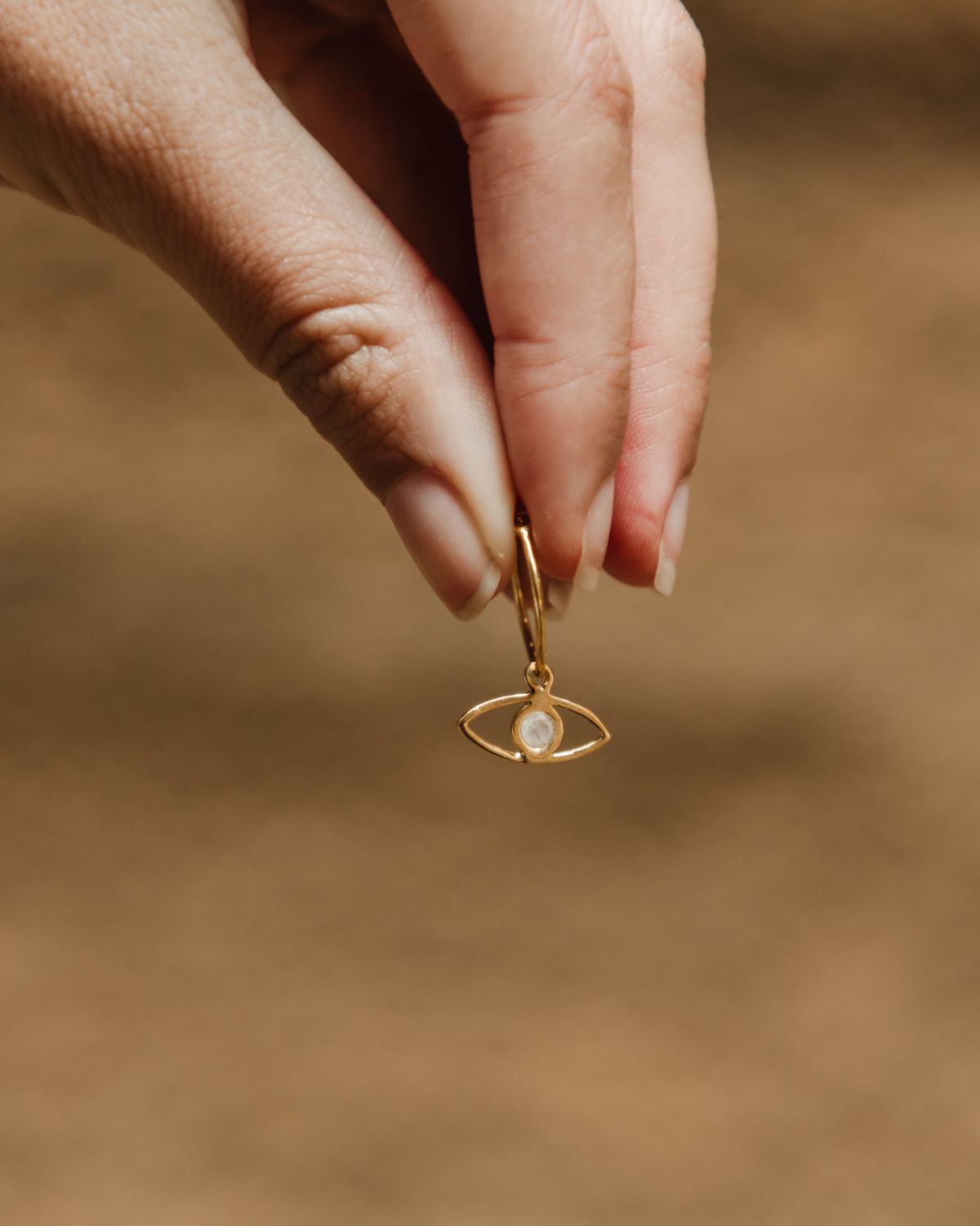 Primer plano de los pendientes en forma de ojo bañados en oro de 18k y con piedra semipreciosa en Piedra de Luna de Isla Vurma