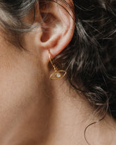 Modelo con los pendientes en forma de ojo bañados en oro de 18k y con piedra semipreciosa en Piedra de Luna de Isla Vurma