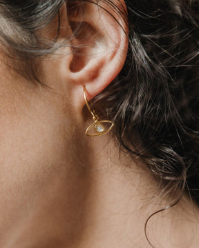 Modelo con los pendientes en forma de ojo bañados en oro de 18k y con piedra semipreciosa en Piedra de Luna de Isla Vurma