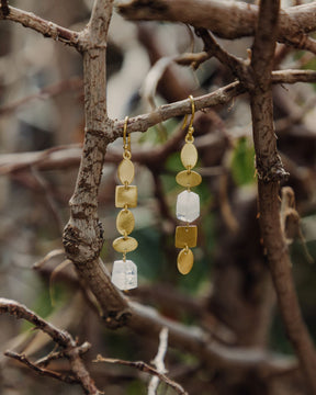 Pendiente dorado de diseño alargado con piezas geométricas rregulares y una piedra semipreciosa Piedra Luna en el centro de una y al final de la otra