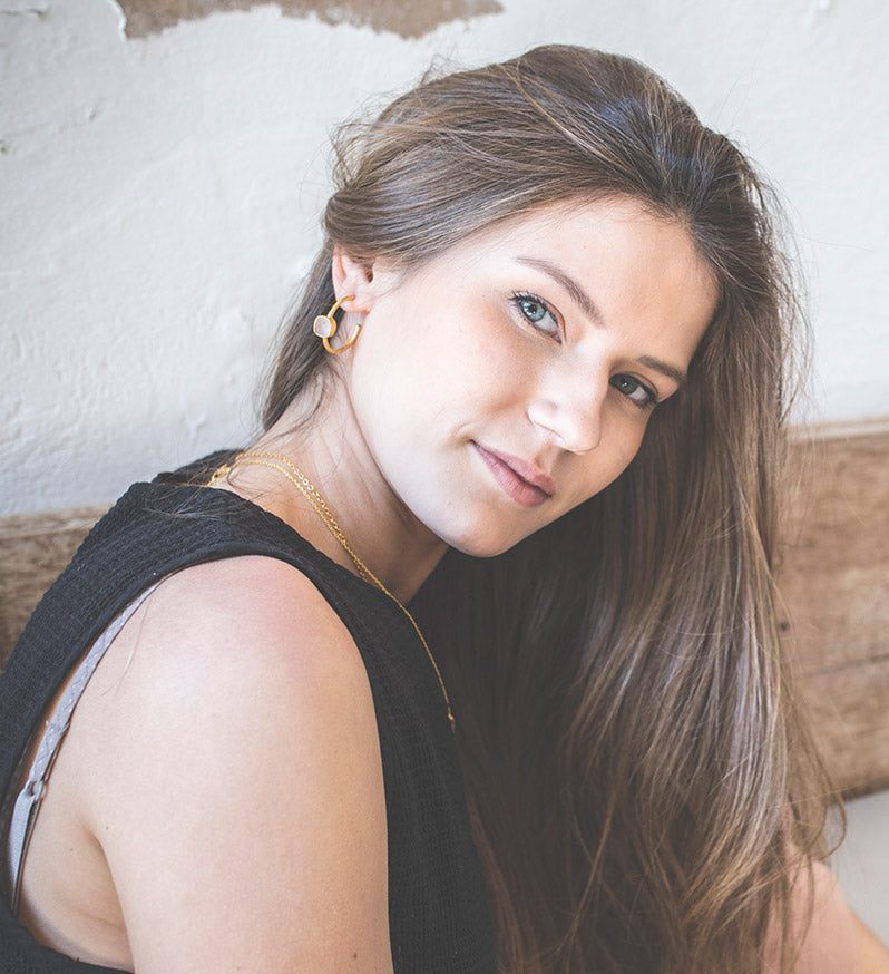 Modelo con los pendientes bañados en Oro de 18 quilates con piedra semipreciosa tallada de forma cuadrada en Cuarzo Rosa de Isla Vurma