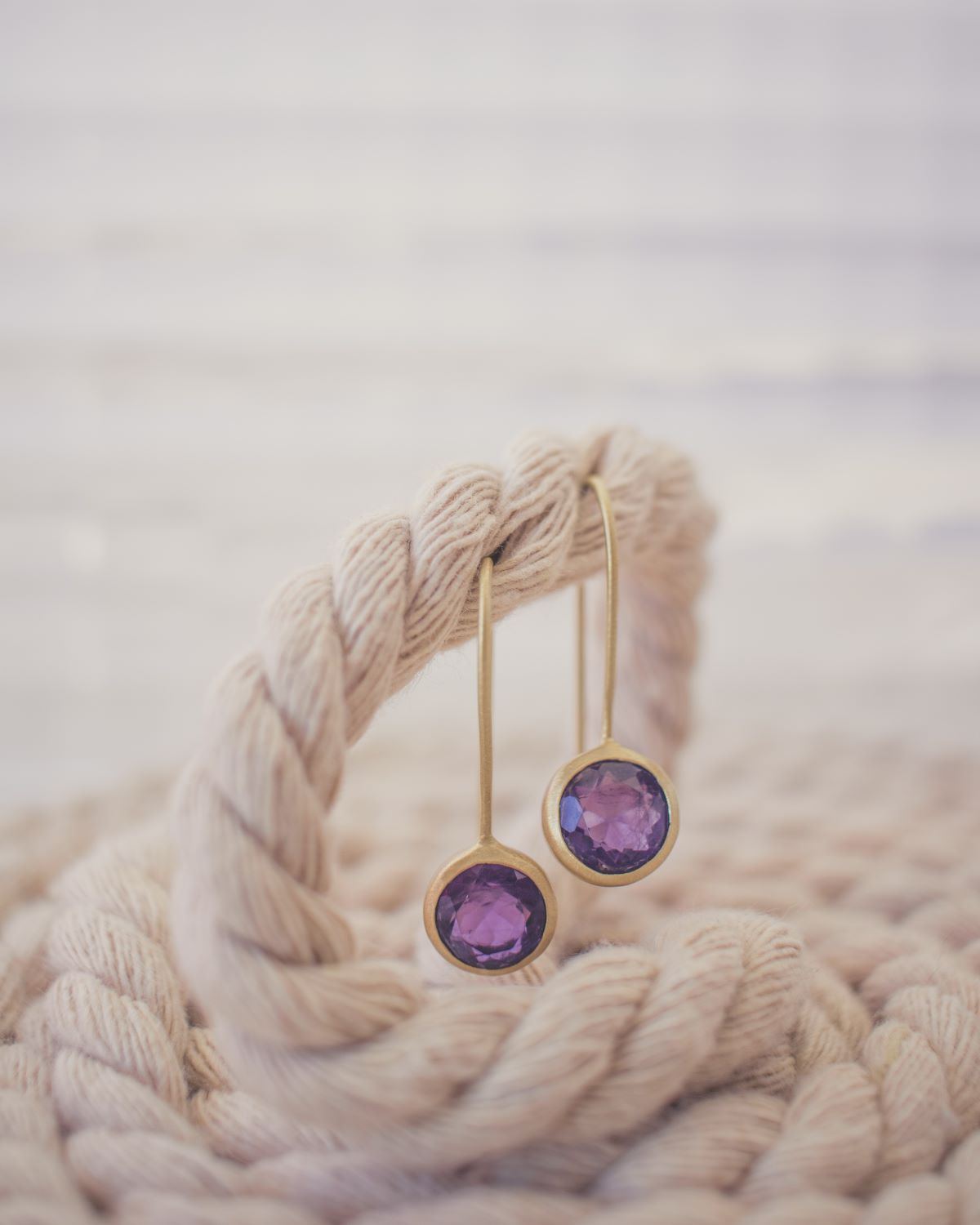 Pendientes de 3 centímetros de largo con amatista pulida en forma circular, elaborados en latón y bañados en Oro de 18 quilates.