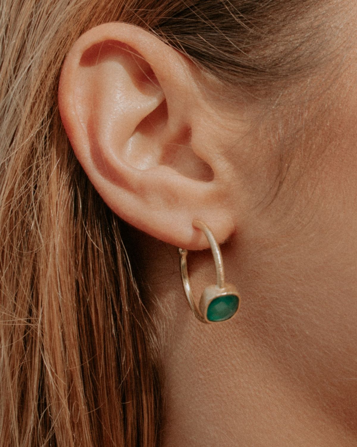 Primer plano de la modelo con el pendiente bañado en Oro de 18 quilates con piedra semipreciosa tallada en forma de cuadrado en Ónix Verde de Isla Vurma