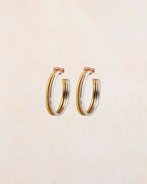 Aros tricolor de tamaño mediano con baño en oro 18k, oro rosa y plata 925 sobre fondo beige claro