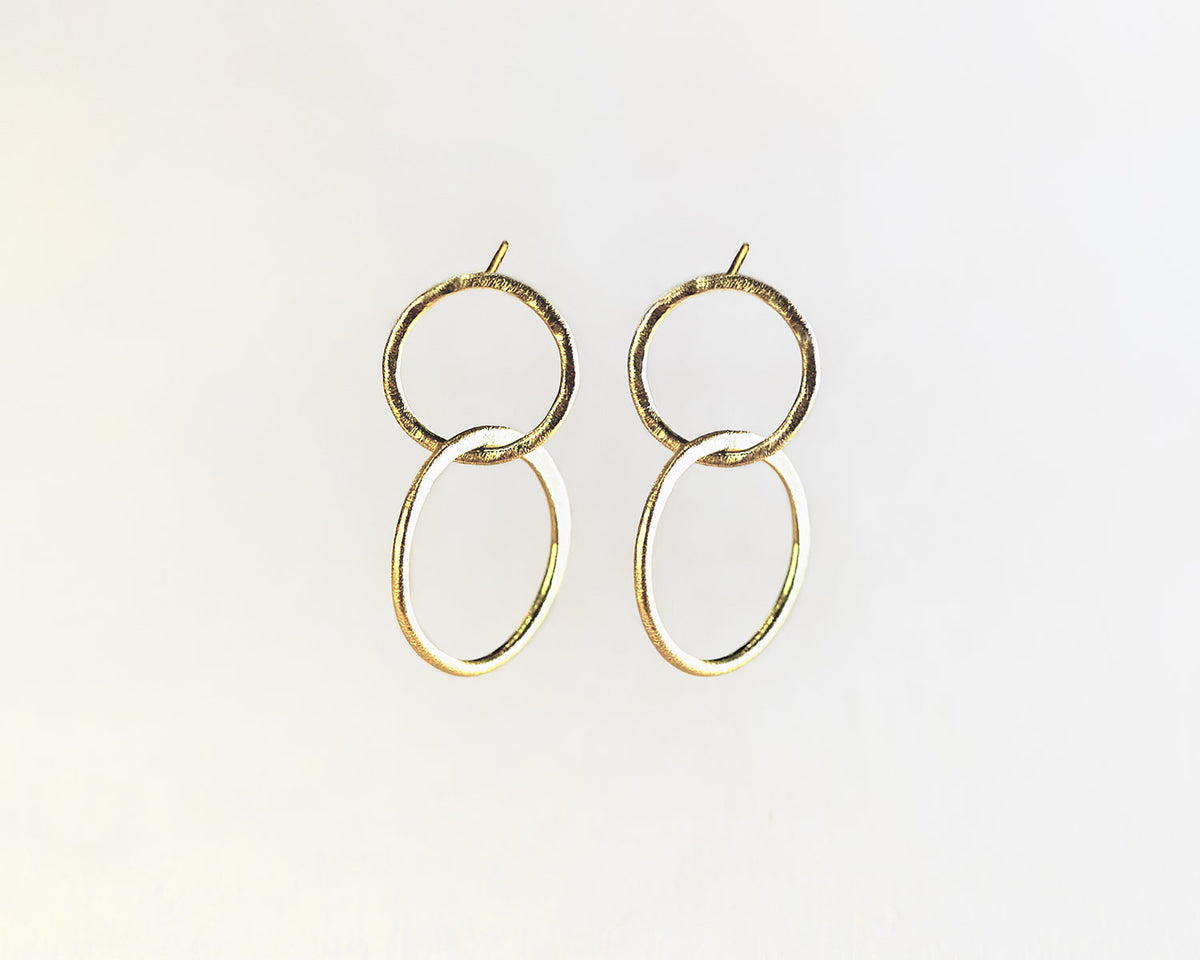 Primer plano de los pendientes bañados en oro de 18k compuesto por dos piezas circulares de Isla Vurma