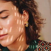 pendientes dorados con diseño de hojas y piedra central en Piedra Luna en la oreja de la modelo bajo luz natural