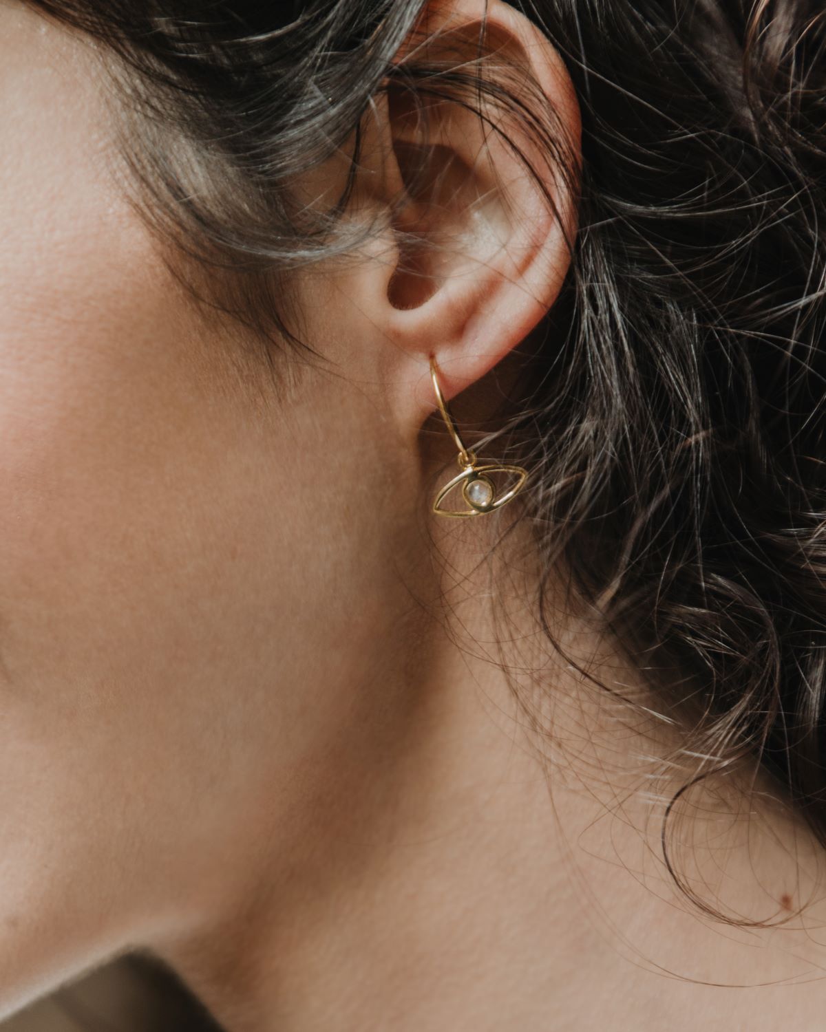 Primer plano de la modelo con los pendientes en forma de ojo bañados en oro de 18k y con piedra semipreciosa en Piedra de Luna de Isla Vurma