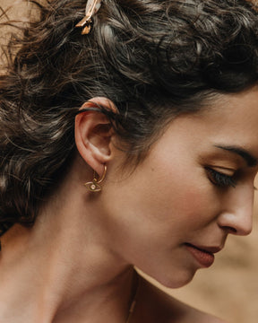 Primer plano de la modelo con los pendientes en forma de ojo bañados en oro de 18k y con piedra semipreciosa en Rosa Calcedonia de Isla Vurma