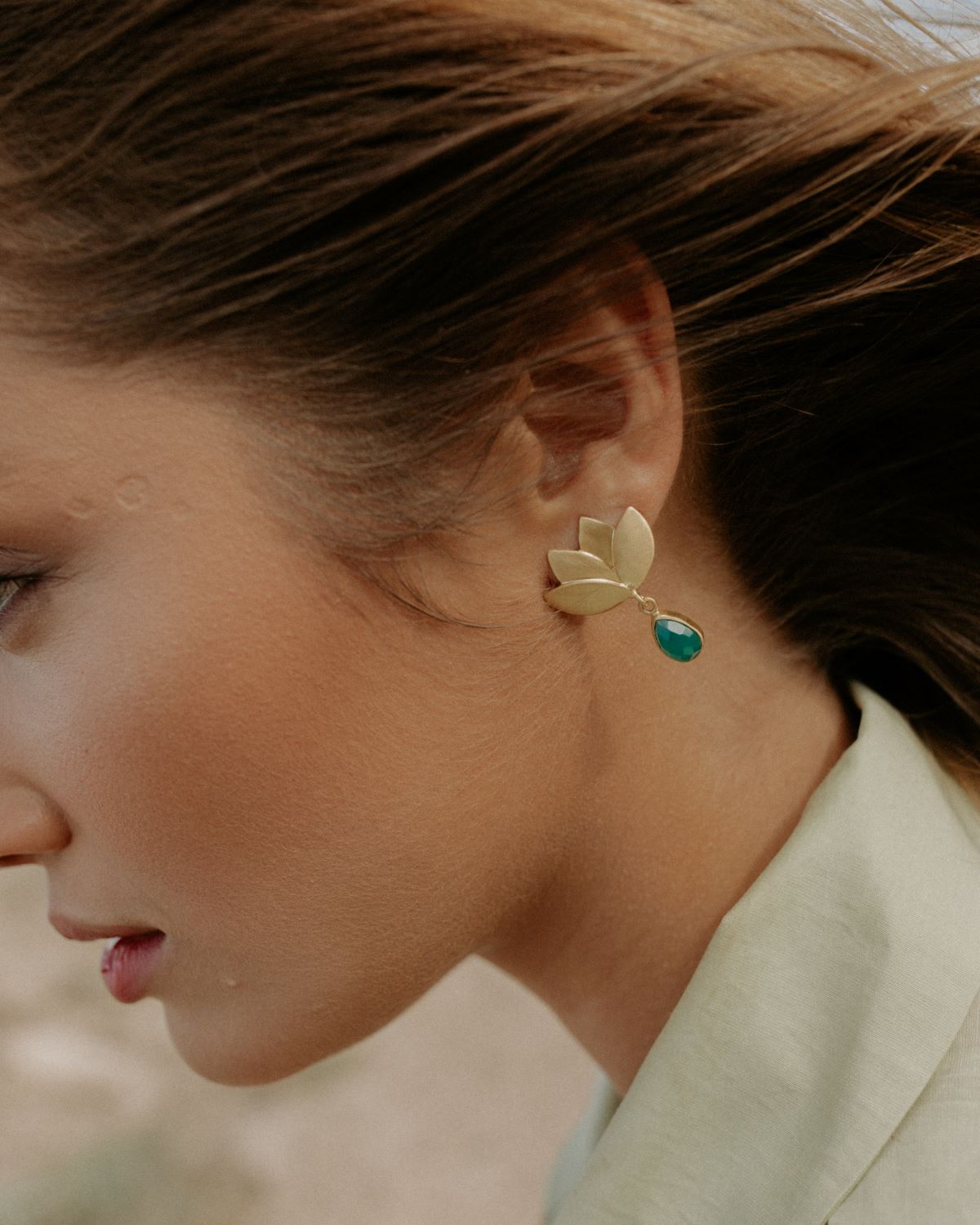 Modelo con los pendientes dorados en forma de flor de loto y piedra semipreciosa en forma de lágrima Ónix Verde de Isla Vurma