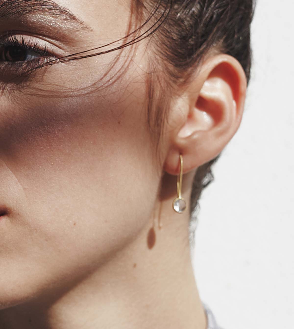 Primer plano de la madelo con los pendientes con piedra semipreciosa Cuarzo Rosa entallada en forma redonda de Isla Vurma