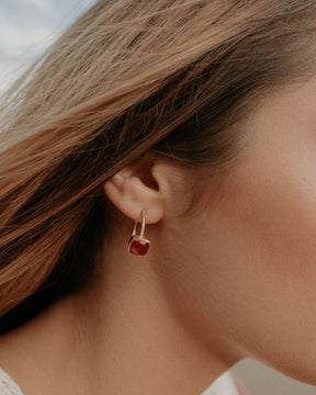 Primer plano de la modelo con los pendientes bañados en Oro de 18 quilates con piedra tallada de forma cuadrada en Cornalina de Isla Vurma