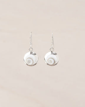 Pendientes pequeños artesanales de Ojo de Santa Lucía montados en plata de ley 925 con diseño en espiral sobre fondo beige claro