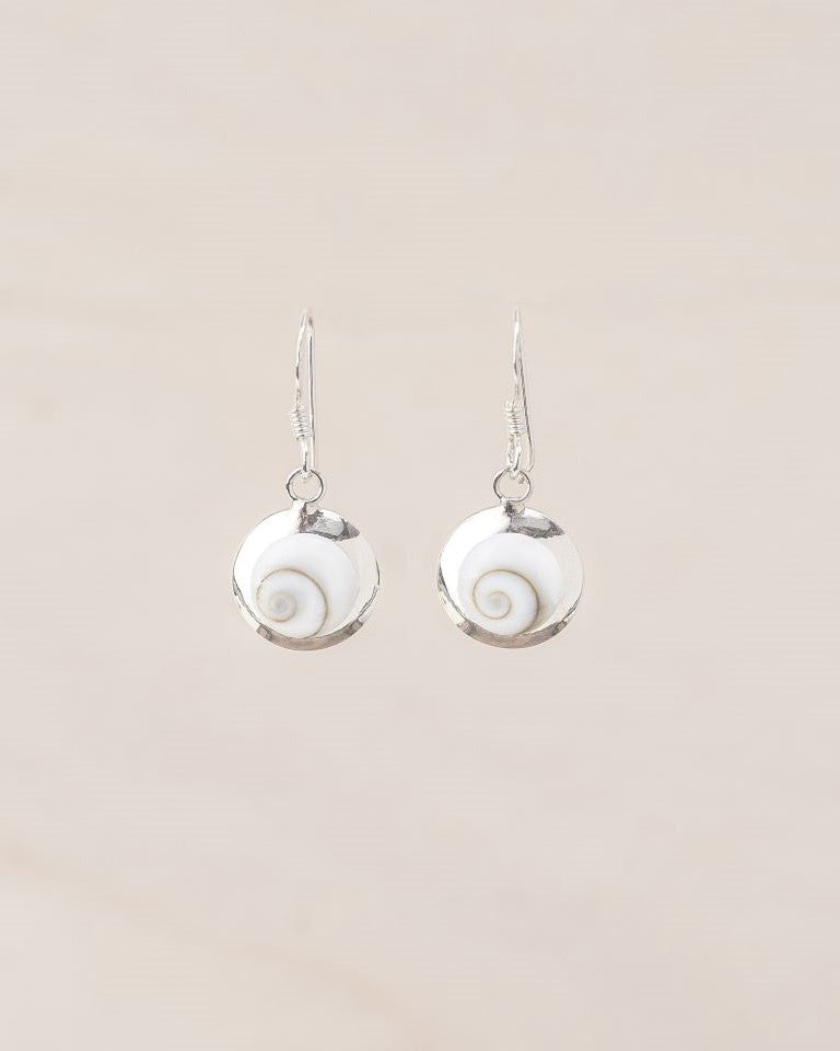 Pendientes pequeños artesanales de Ojo de Santa Lucía montados en plata de ley 925 con diseño en espiral sobre fondo beige claro
