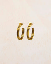 Aros dorados gruesos de acabado pulido sobre fondo beige claro