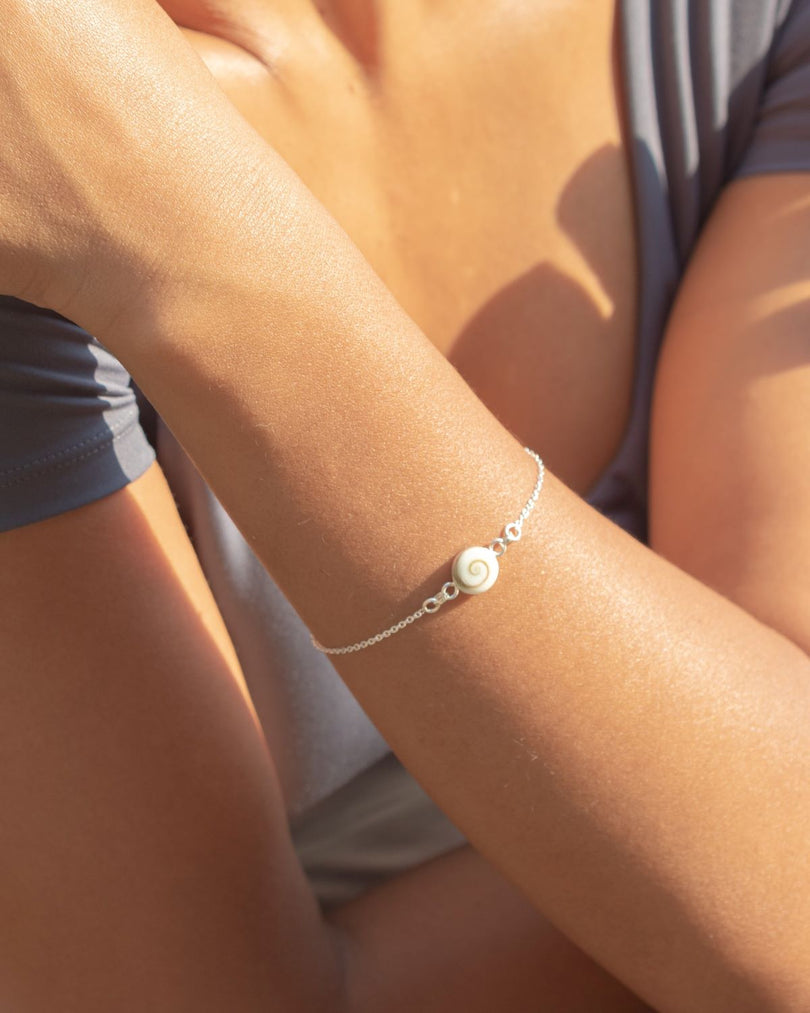 Pulsera de concha de Santa Lucía en plata lucida en la muñeca de la modelo bajo la luz del sol