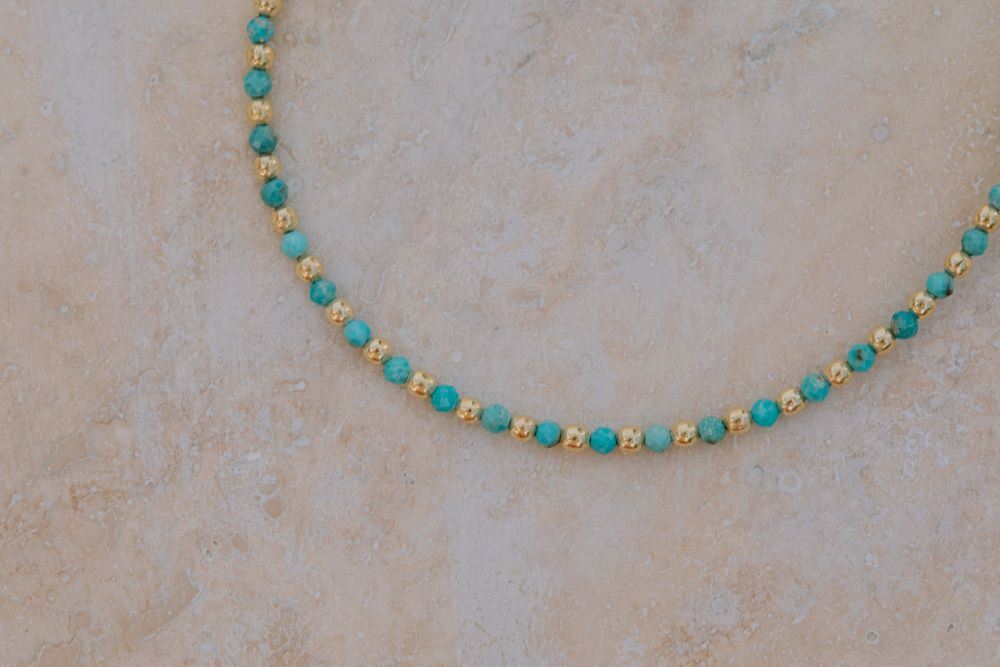 Primer plano una pulsera con cuentas facetadas de piedra semipreciosa en Aqua Calcedonia y bañadas en Oro de 18 quilates