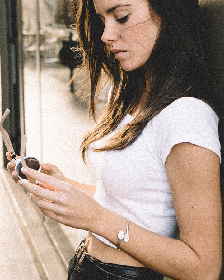 Modelo con pulsera rígida de plata de ley 925 y piedra de Santa Lucía en un look diario
