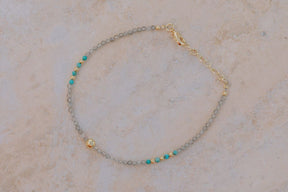 Primer plano una pulsera con cuentas facetadas de piedra semipreciosa en Labradorita, Aqua Calcedonia y bañadas en Oro de 18 quilates