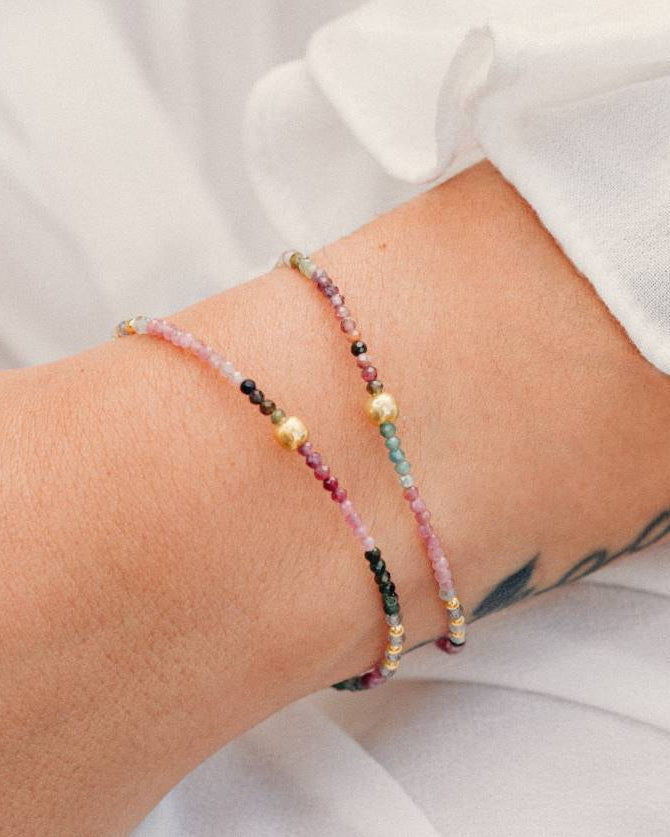 Primer plano de un conjunto compuesto por dos pulseras con cuentas facetadas de piedra semipreciosa en Turmalina Multicolor y bañadas en Oro de 18 quilates